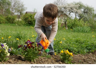 Boy carefully watered flowers on the lawn