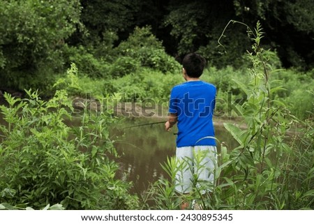 Boy casting fishing line into creek on a summer day.