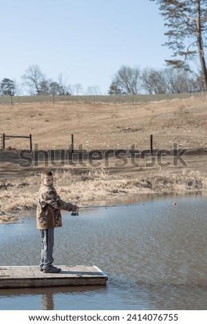 boy casting fishing rod from dock in pond