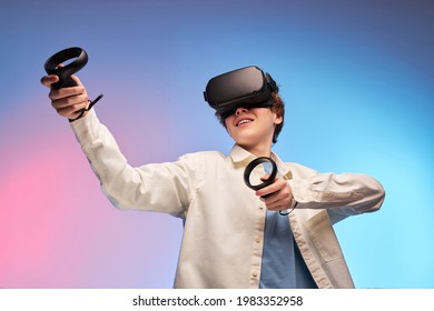 boy in casual outfit using VR glasses exploring augmented reality, using smart devices, controllers in hands. Modern cyber technologies concept, Virtual reality games. isolated on colourful background - Powered by Shutterstock