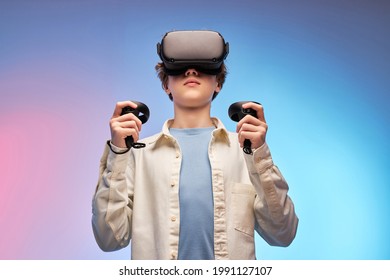 Boy In Casual Outfit Using VR Glasses Exploring Augmented Reality, Using Smart Devices, Controllers In Hands. Modern Cyber Technologies Concept, Virtual Reality Games. Isolated On Colourful Background