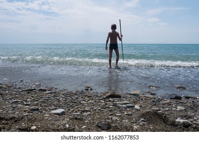 Boy Catches Fish With A Spear On The Sea Beach