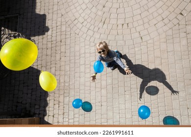 boy catches lot yellow   blue balls falling him from above  Ukrainian children against war  Drawing attention to war in Ukraine  happy childhood  have fun  sunny day  shadows  Top view