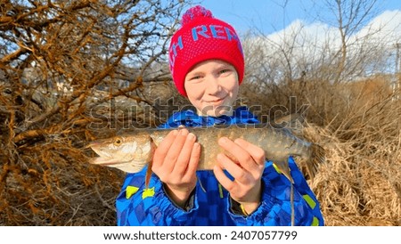 A boy caught a small pike while winter fishing at a dam in the Czech Republic.