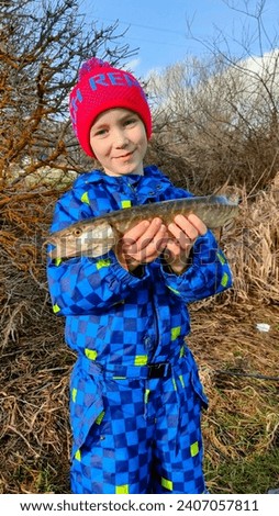 A boy caught a small pike while winter fishing at a dam in the Czech Republic.