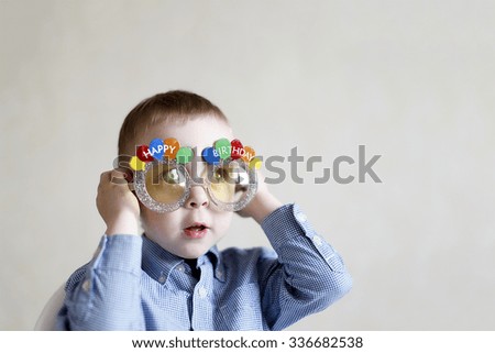 boy celebrates his birthday. little boy puts on festive fun eyeglasses to celebrate your birthday