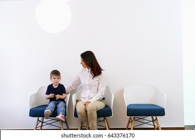 A Boy Child In Doctors Waiting Room - Reception With His Mom. Kids First Visit For A Regular Dentist Exam 