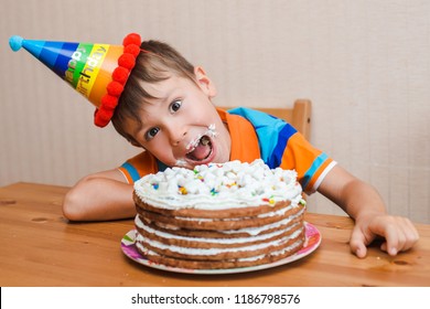 Boy The Child Is Eating His Birthday Cake. The Smeared Face In A Sweet Cream.