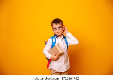 A Boy A Child A Schoolboy With Glasses And A Book In His Hands Eavesdropping On A Yellow Background