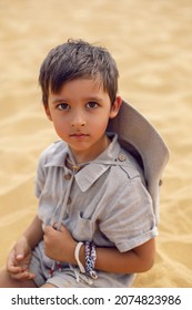 Boy Is A Child Traveler In A Suit Of An Archaeologist Tracker And Wearing A Hat Sitting On The Sand In The Desert