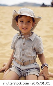 Boy Is A Child Traveler In A Suit Of An Archaeologist Tracker And Wearing A Hat Sitting On The Sand In The Desert