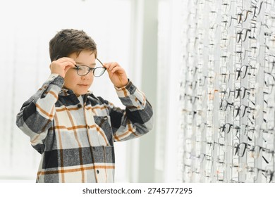 Boy choosing new optical frames for vision correction, selecting from display in ophthalmology clinic