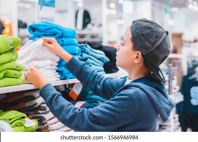 A Boy Choosing And Picking Right Clothes In The Store. Shopping And Sales Concept.