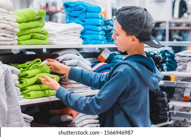 A Boy Choosing And Picking Right Clothes In The Store. Shopping And Sales Concept.