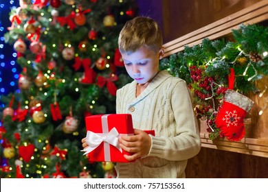 boy with Christmas gift Opening Christmas Present In Front Of Tr
