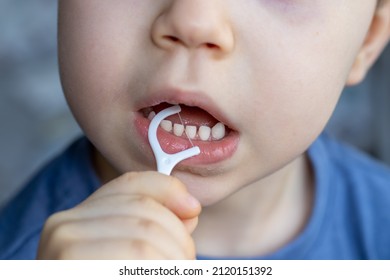 a boy is cleaning his teeth with a toothpick. plastic dental floss. close up photo. kid has diastema. space between teeth. stomatological concept. dental care, family education. - Shutterstock ID 2120151392