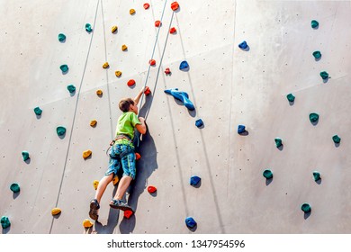 The boy climber climbs on an artificial tower, overcoming obstacles on his way up - Powered by Shutterstock