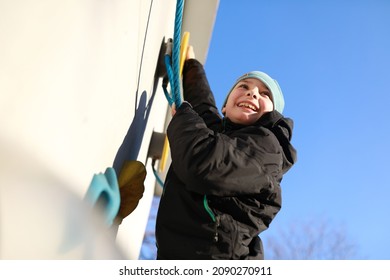 Boy Climbing Rope On Wall At Playground