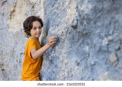 A boy climbs a rock, a little rock climber is training to climb a boulder, a child goes in for sports - Shutterstock ID 2161023531