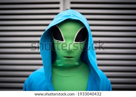 Boy close up portrait with alien mask against stripes background.