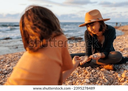 boy collects shells and pebbles in the sea on a sandy beach with his mother. Family having fun on the beach collecting shells. mother and son.