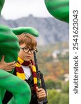 Boy, Costume, Wizard, dressed as Harry Potter, with a wand, standing next to a green dragon statue.