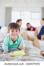 Boy Counting Change In Piggy Bank On Sofa In Living Room