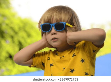 The boy covered his ears with his hands. The child does not want to hear from teachers and parents. The child wants silence, do not yell at children - Shutterstock ID 2369972753