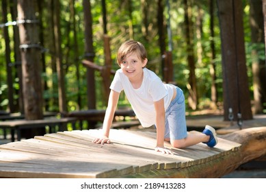 the boy crawls on a log in the forest, the child spends the summer in the camp - Powered by Shutterstock