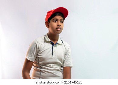 A boy in cricket uniform with cap