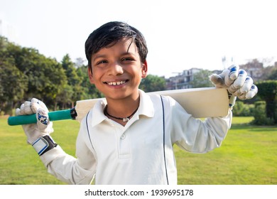 Boy In Cricket Uniform Holding A Cricket Bat 