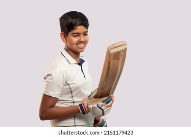 A boy in cricket uniform holding Cricket Bat looking into bat