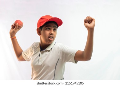 A boy in cricket uniform standing Holding a ball