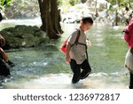 A boy crossing the stream in the forest