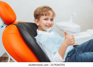 A Boy With Curly Red Hair In A Dental Chair Shows Class. Children's Dentistry