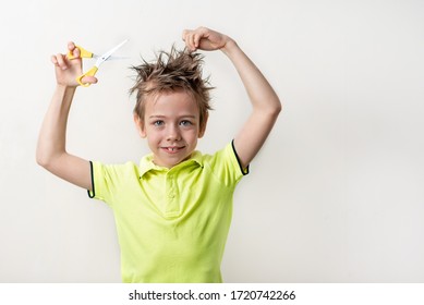 The boy cuts his own overgrown hair, there is no way to go to the hairdresser, because quarantine, self-isolation. Concept home quarantine. A boy dressed in a bright T-shirt, holding scissors - Powered by Shutterstock