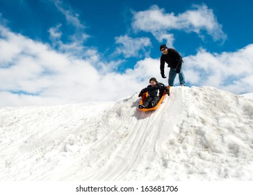 Boy And Dad Sledding In Winter