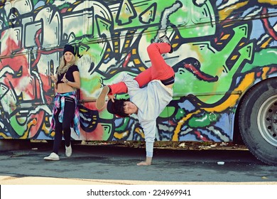 Boy dancing break dance in front of a beautiful girl with stylish bus on the street - Powered by Shutterstock