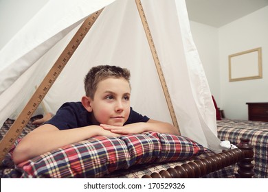 Boy Daydreaming In A Fort Made Of Sheets