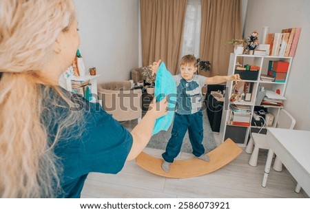boy developing motor skills and coordination by playing on a wooden wobble board during a therapy session, interacting with a therapist