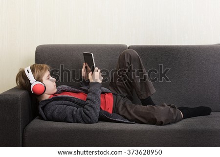 Boy with a digital tablet lying on the couch