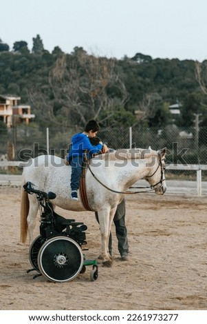 Boy with disabilities embracing his equine therapy instructor at equestrian center.