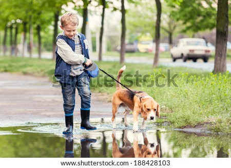Boy with dog walks through the puddle