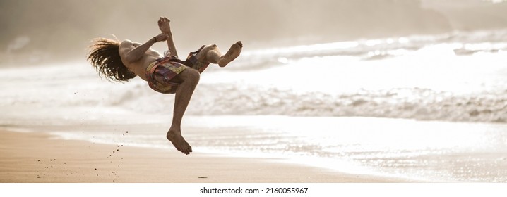 boy doing backflip at the beach