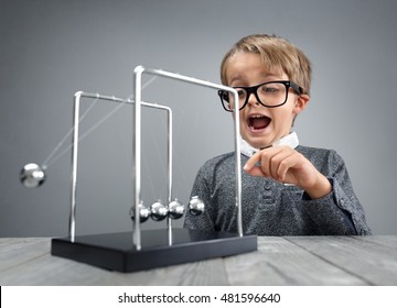 Boy doing experiment with Newton's cradle physics concept for education, action and reaction or cause and effect