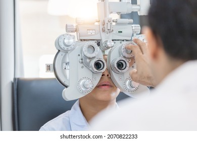 Boy doing eye test checking examination with optometrist in optical shop, Optometrist doing sight testing for child patient in clinic