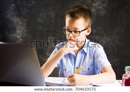 Boy doing homework with laptop computer at home