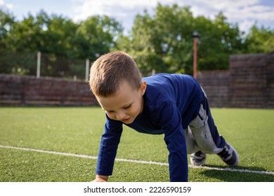 Boy doing push ups on a small football field on a beautiful sunny day - Powered by Shutterstock