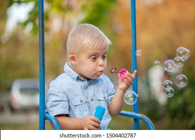 Boy With Down Syndrome Blowing Soap Bubbles, Cute European Child With A Genetic Abnormality, Disabled Children, Extra Chromosome, Psychiatric Illness In Children.
