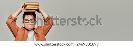 A boy with Down syndrome holding a stack of books on his head.